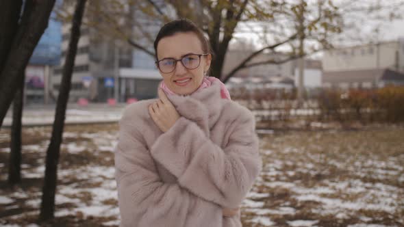 Woman in a Fur Coat and Sunglasses in the City Poses for the Camera