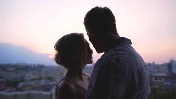 Couple Admiring Pink Sunset Gently Enveloping Them View from Roof