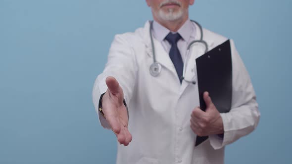 Adult doctor in medical uniform and with stethoscope reaches out for handshake