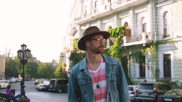 Young Stylish Handsome Redbeard Man with Bag and in Hat Walking in Old City Center Slow Motion