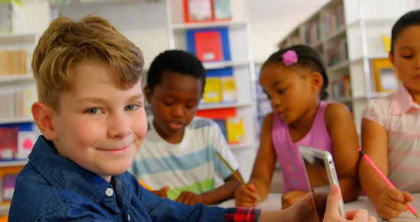 Caucasian schoolboy using digital tablet in school library 4k