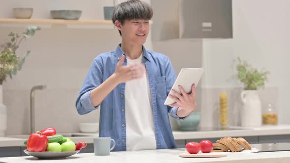 Young Asian Man Doing Video Call On Tablet in Kitchen