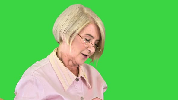 Senior Woman Sitting and Knitting and Telling a Story To Camera on a Green Screen Chroma Key