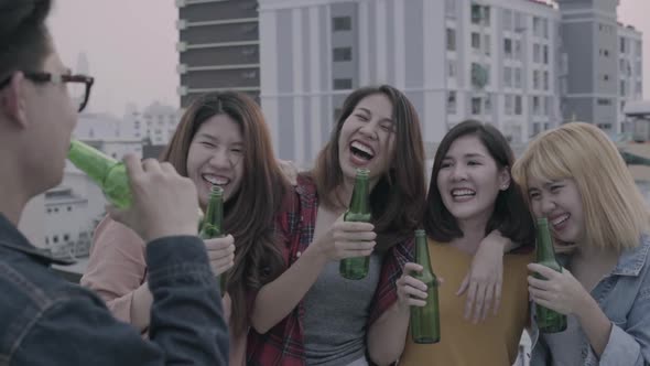 young asian women and man people dancing and raising their arms up out with drinks beer.