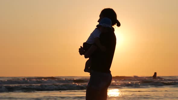 Young Mother Holding Her Son in Her Arms By the Sea.