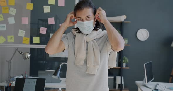 Slow Motion Portrait of Young Entrepreneur Putting on Medical Mask in Office During Pandemic