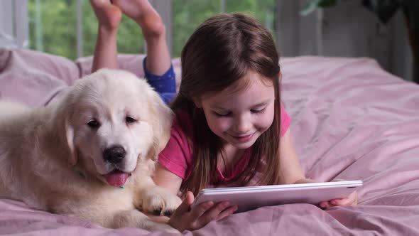 Smiling Girl Watching Cartoon on Tablet with Puppy