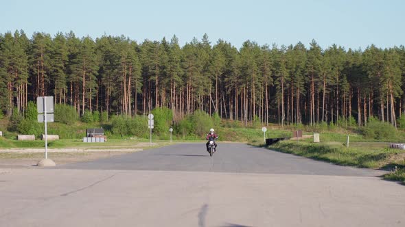 Motorbike rider with helmet on road in the forest approaching the camera
