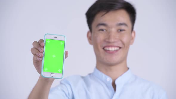 Face of Young Happy Asian Businessman Showing Phone