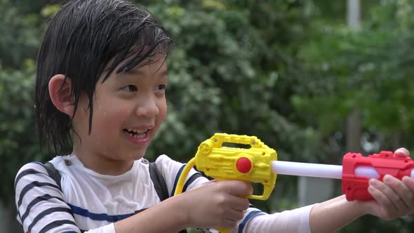 Cute Asian Child Playing With Water Gun In The Summer