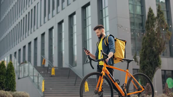 The Food Delivery Guy is Going and Looking at the Smartphone