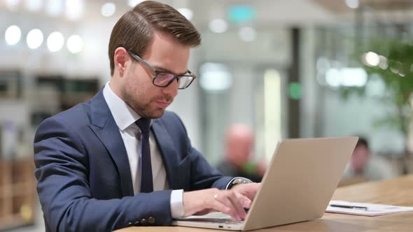 Businessman with Laptop Pointing at the Camera 