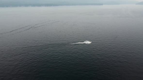 Clockwise drone shot of a jet ski driving on Payette Lake in McCall, Idaho on a smoky day. This stun