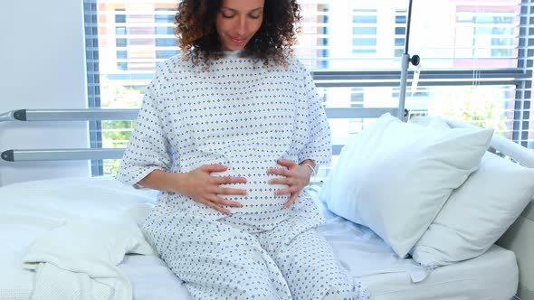 Pregnant woman touching her belly in ward