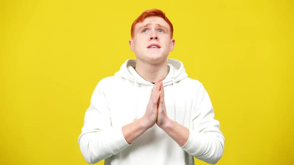 Portrait of Hoping Redhead Man Praying at Yellow Background in Slow Motion