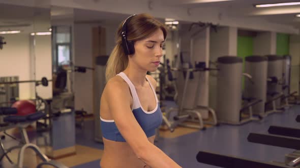 Sportswoman Going on Cardio Machines Listen Playlist Via Earphones