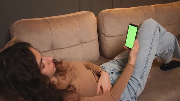 Woman Lying on a Couch with Green Screen Smartphone