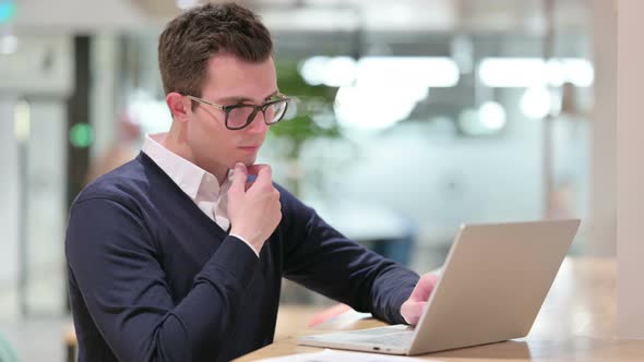 Pensive Young Businessman Thinking and Working on Laptop 