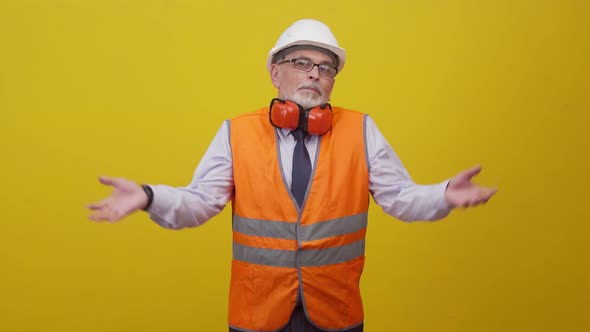 Adult man engineer in uniform shows a gesture of unknowing, spreading arms to the sides in studio.