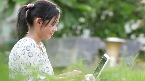 Beautiful Asian Girl Sitting In Park On The Green Grass With Laptop