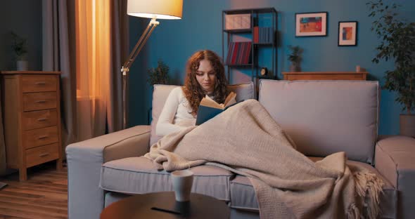 Tired Attractive Woman Lies on Couch in Evening Covered with Blanket Resting Relaxing After Work alt