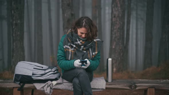 Young Cheerful Woman Using Her Smartphone in a Misty Autumn Forest