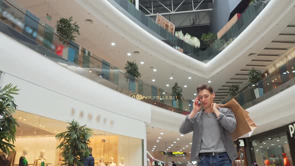 Young Man Talking on the Phone at the Shopping Mall