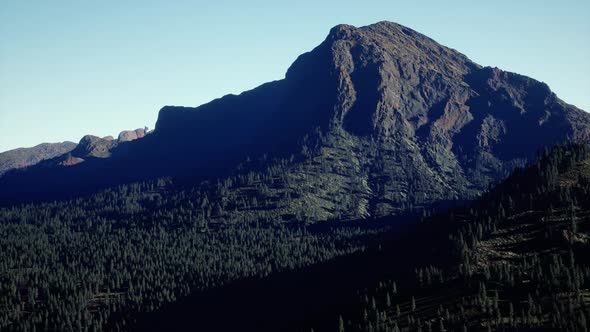 Panoramic Aerial View of Rocky Ridge Among Green Forest at Sunset