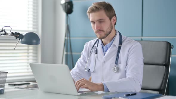 Doctor Showing Thumbs Down Sign While Using Laptop at Work