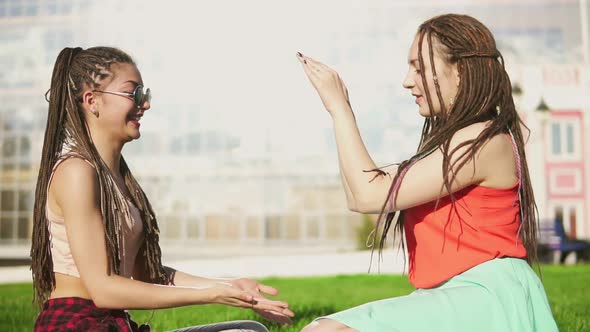 Happy Women with Dreads Sitting on Grass in Summer Park