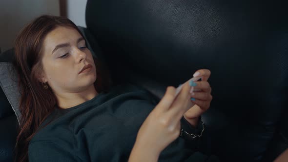 Closeup Shot of the Young Redhead Lying on the Couch Playing Video Games on the Phone