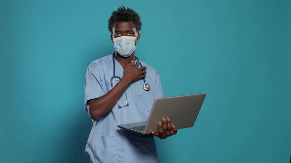 Man Nurse Wearing Face Mask and Holding Laptop