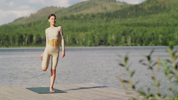 Woman Practicing Balancing Yoga Asana on Lake Pier