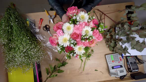 Close-up of the hands of a female florist packing a beautiful composition