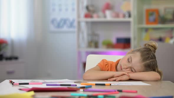 Adorable Schoolgirl Sleeping on Desk, Color Pencils and Paper Table, Education