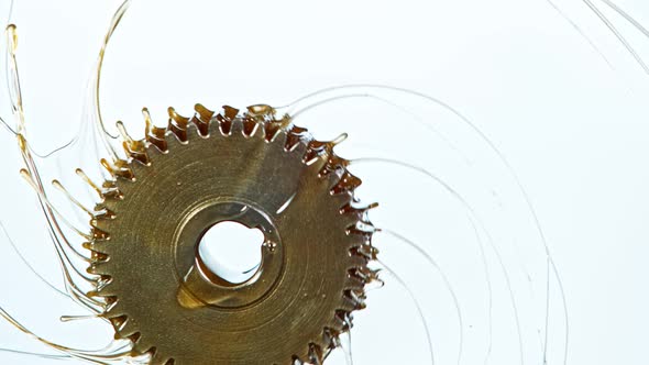 Super Slow Motion Shot of Rotating and Splashing Metal Cogwheel on White Background at 1000 Fps