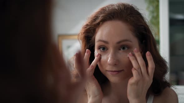 Woman applying eyes cream in the bathroom. Shot with RED helium camera in 4K.