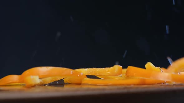 Yellow Bell Pepper Slices Fall on Brown Board with Water