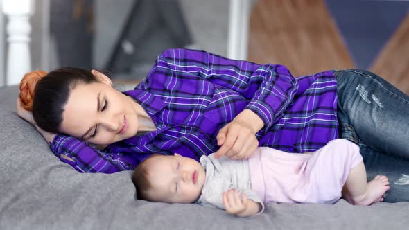 Caring Smiling Female Parent Kissing and Caress Her Sleeping Little Baby Medium Shot