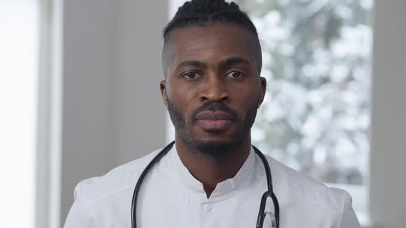 Serious African American Male Physician Standing Indoors Looking at Camera