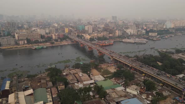 Busy bridge crossing Bangladesh river in a polluted atmosphere. Aerial