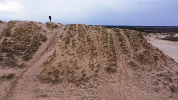 Aerial Wide Shot Of a Tourist Standing on Top of a Sand Dune and Enjoying View