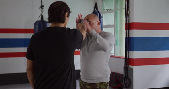 Caucasian man learning self defense from trainer in gym