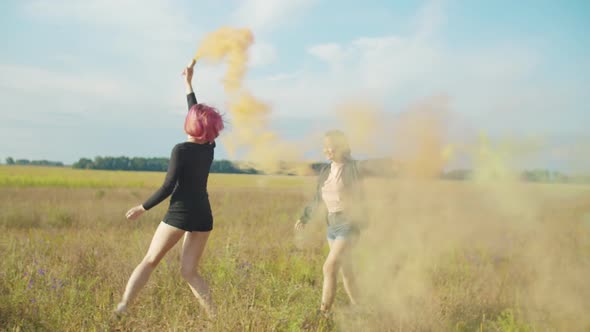 Women Swinging with Colored Smoke Bombs Outdoors