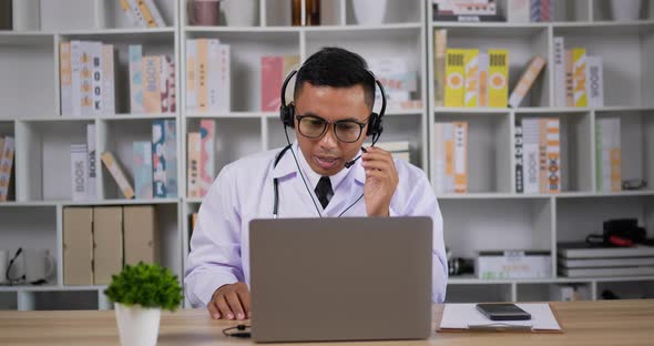 Doctor with headset making conference call on laptop