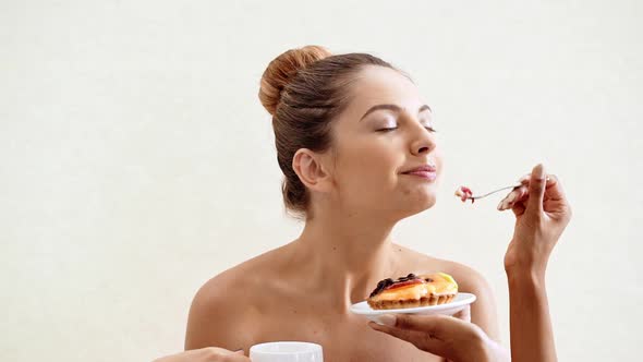 Hands Giving Cake and Cup of Coffee to Young Beautiful Naked Girl in Towel Over White Background