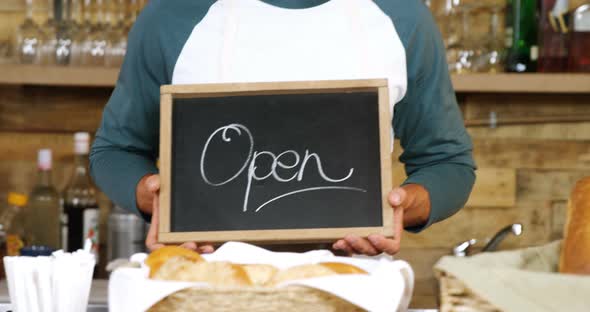 Male waiter standing with open sign board 