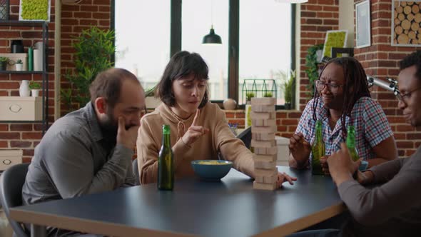 Happy People Having Fun with Wooden Tower on Table