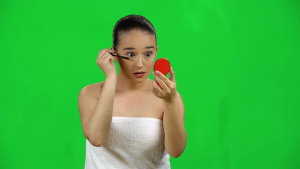 Woman Applying Mascara on Eyelashes Looking in a Red Mirror, Green Screen