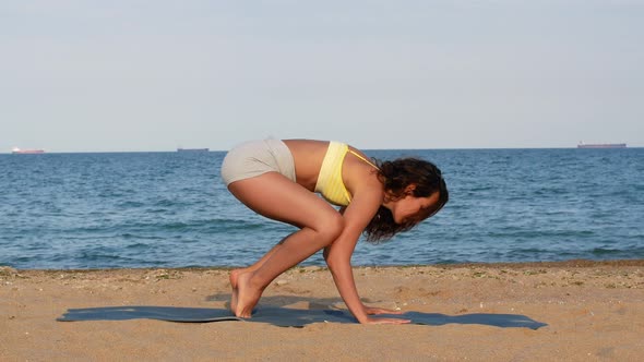 Beautiful tanned young woman sitting in a meditation pose on the beach. Goods for health.